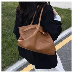 Brown large capacity tote bag with soft leather texture and drawstring detail in outdoor setting