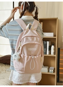 Detail of pink nylon backpack with drawstring side and cloud plush pendant charm