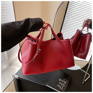 Detail of burgundy leather bucket bag with top handle and adjustable shoulder strap