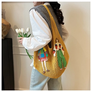 Detail of yellow knit tote bag featuring colorful artistic figure embroidery on shoulder