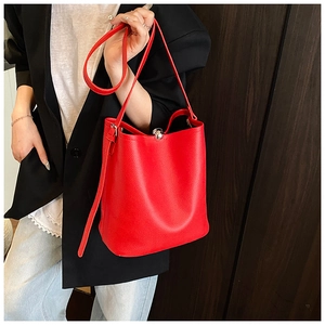 Gros plan du sac seau en cuir rouge avec fermoir sphérique argenté et bandoulière