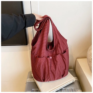 Detail of red and black checkered tote bag with dual front button pockets and canvas texture