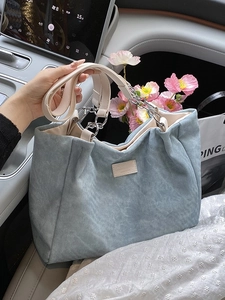 Minimalist light blue fabric tote bag with cream leather straps and metal chain detail