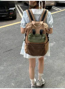 Detailed view of a multi-pocket canvas backpack featuring khaki and olive green color-blocking