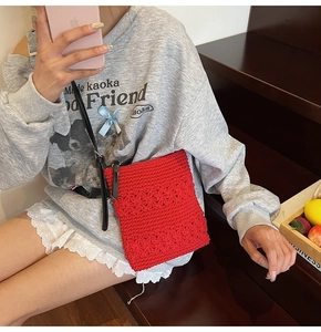 Detail of red hollow crochet knit crossbody bag with 3D floral pattern and leather strap