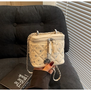 Dettaglio della mini borsa trapuntata beige con strass e ciondolo a camelia