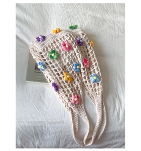 Close-up of crochet hollow mesh bag with colorful knitted flower patterns and cotton straps
