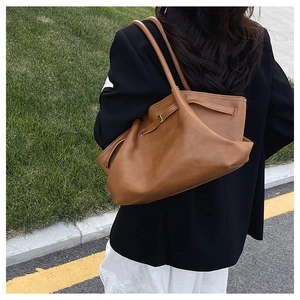 Outdoor shot of a slouchy caramel brown leather tote bag with elegant gold buckle detail