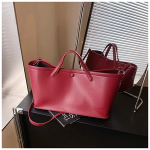Close-up of matte dark red leather tote bag on a black cabinet with mirror reflections