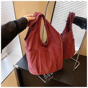 Detail of red checkered canvas tote bag with functional front pocket and wide shoulder strap