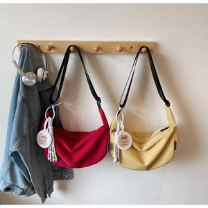 Detail view of red and yellow crescent bags with Capybara charms on wooden hangers
