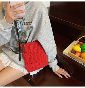 Red crochet knit crossbody bag with floral texture worn by a model in casual setting