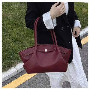 Close-up of a burgundy leather tote bag with metallic buckle and textured finish