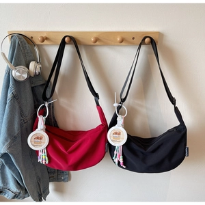 Detail of red and black nylon crescent bags with cute Capybara charms on wooden hooks