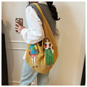 Detail of yellow knit tote bag featuring cute cartoon embroidery and crochet texture
