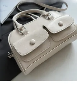 Detail view of beige faux leather handbag with dual front pockets and smooth texture
