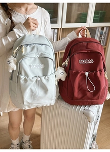 Detail of light blue and dark red pleated nylon backpacks with star plush charms