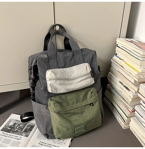 Detailed view of tri-color canvas backpack with dual handles and multiple zipper pockets