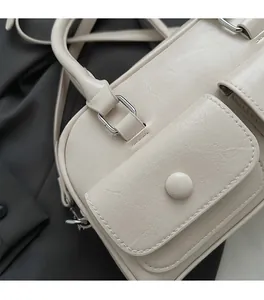 Detailed view of cream leather texture and silver hardware on minimalist shoulder bag