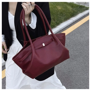 Detail of burgundy textured leather tote bag with unique pleated design and silver hardware