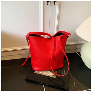 Détail d'un sac seau en cuir rouge avec boucle boule argentée sur un livre noir élégant