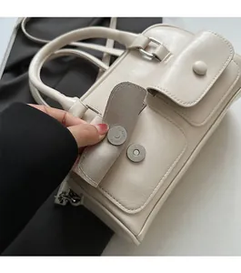 Detail view of the magnetic snap closure on a cream leather shoulder pillow bag