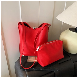 Détail d'un ensemble de sacs seau en cuir grainé rouge avec pochette sur fond minimaliste