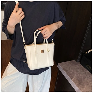 Close-up of white pebble grain PU leather bucket bag with elegant gold metal buckles