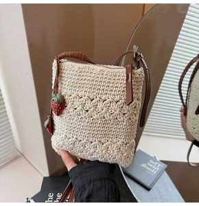Detailed close-up of cream crochet bag with floral patterns and cute strawberry charms