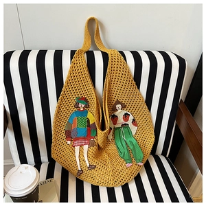 Detail of yellow knit tote bag featuring cartoon embroidery on black striped background