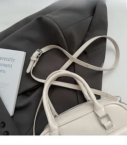 Detail of cream leather shoulder bag with adjustable strap and silver hardware on a blazer