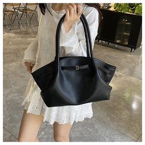 Detail of black tote bag with unique pleated side folds and elegant metal buckle strap