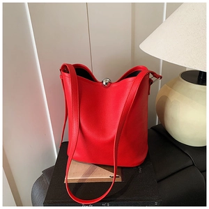 Gros plan du sac seau en cuir grainé rouge avec fermoir décoratif en boule de métal argenté