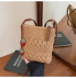 Detail of hand-woven crossbody bag featuring 3D crochet flowers and strawberry charms
