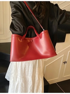 Red leather large tote bag with top handles and shoulder strap shown on a model