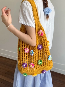 Handmade yellow crochet tote bag with colorful floral knit patterns for summer vacation