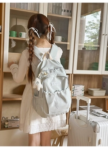 Detail of light blue nylon backpack featuring side water bottle pocket and star charm