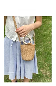 Sac seau en rotin tressé avec poignées en perles de bois et bandoulière en extérieur