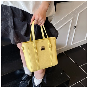 Detail of bright yellow lychee grain PU leather tote bag with metallic square accent