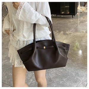 Detail view of a dark brown tote bag with slim shoulder straps and gold buckle accent