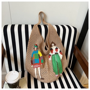 Close-up of knit hobo shoulder bag with cute girl cartoon patches and woven texture