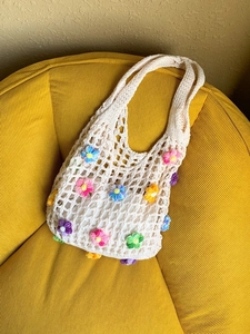 Handmade crochet mesh tote bag with colorful floral embroidery for beach vacations