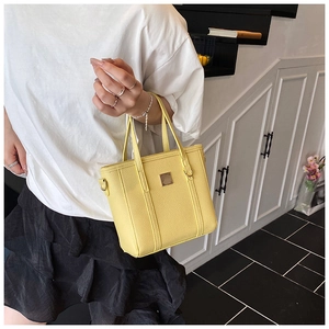 Close-up of yellow lychee-patterned bucket bag with metal square accent for women