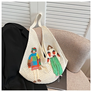 Detail of cream knit tote bag featuring colorful cartoon embroidery on woven mesh fabric