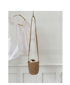 Détail du sac seau en paille avec poignée en perles blanches et bandoulière tissée