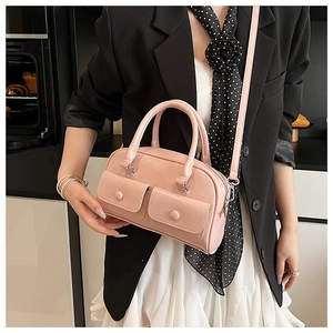 Detail of pink faux leather pillow bag with double front pockets on a model with black suit