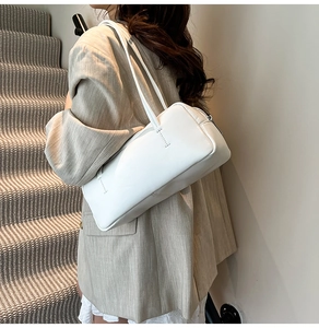 Minimalist white leather shoulder bag with sleek straps shown in an elegant lifestyle setting