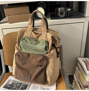 Close-up of color-block nylon backpack featuring dual front pockets and top handles