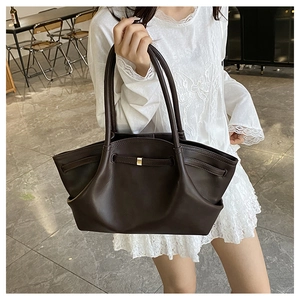 Detail of dark brown tote bag showing smooth leather texture and gold hardware accents