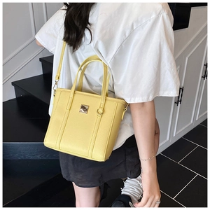 Close-up of vibrant yellow bucket bag with pebbled texture and silver buckle detail